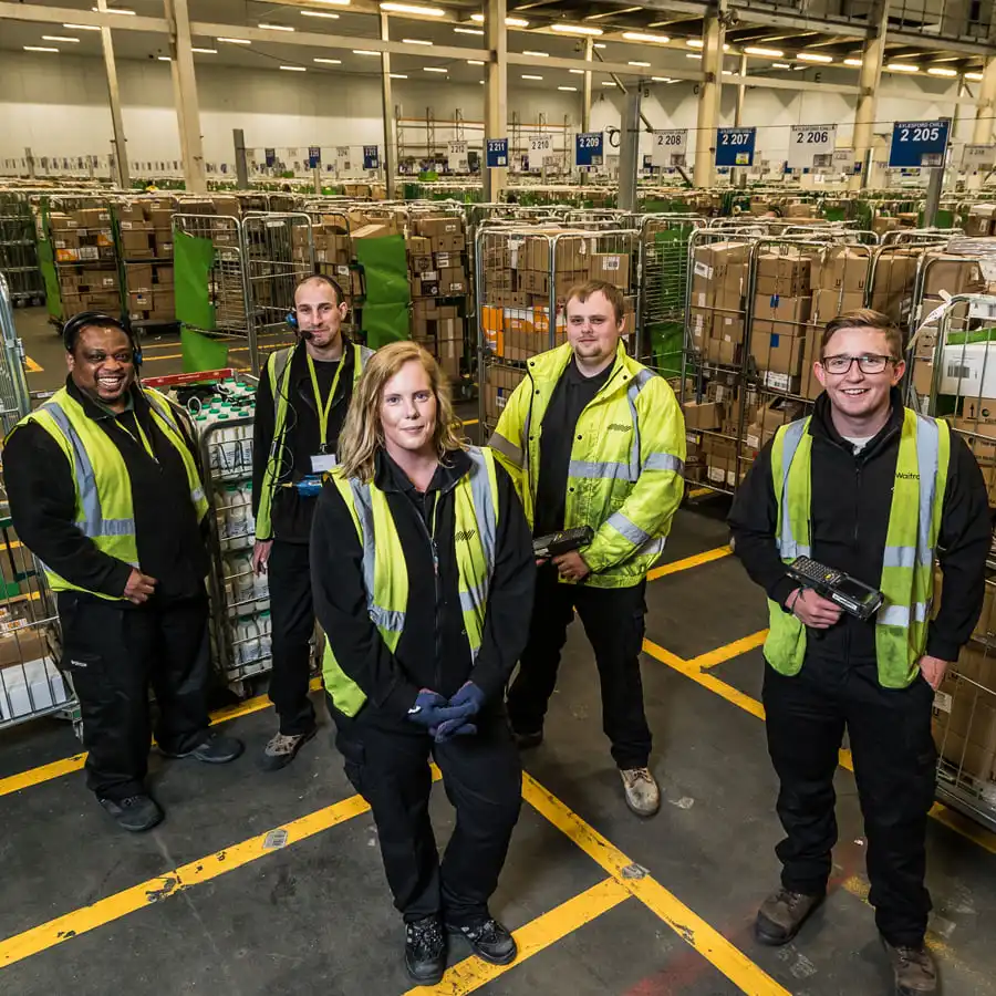 Group of Warehouse Assistants in hi-viz jackets looking up at the camera