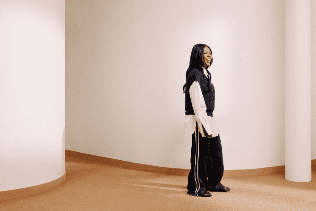 Ruth standing on a photography shoot set with a blank background smiling away from the camera.