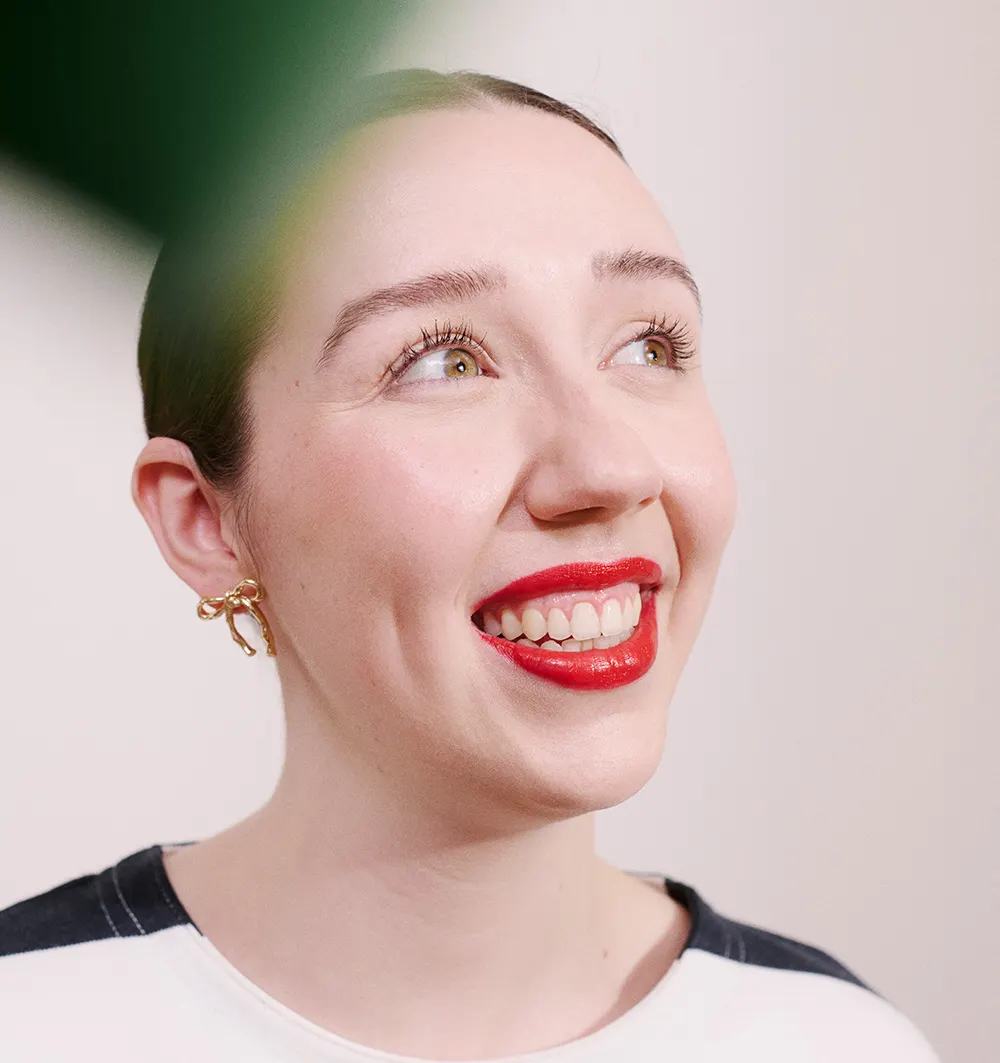 Someone smiling with a leaf falling over the lens