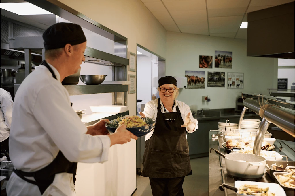 Catering team passing over food to the service counters.