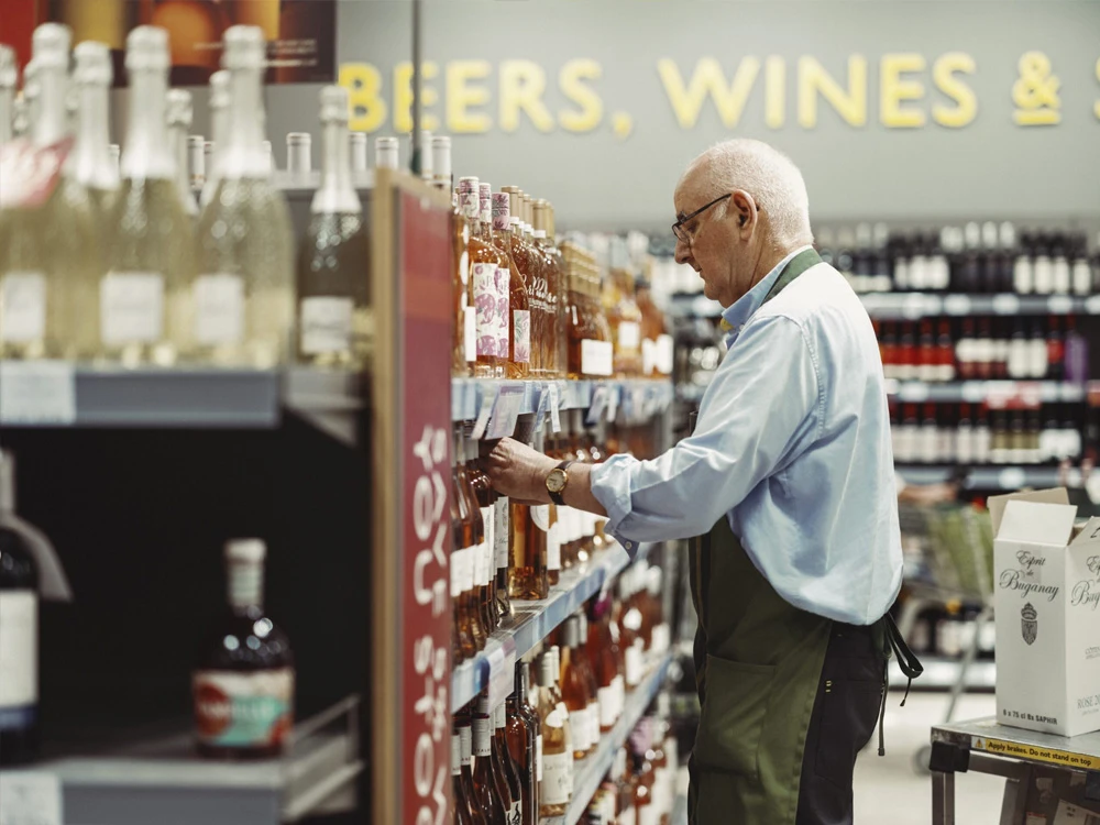 Older man restocking wine section