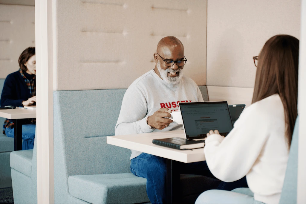 Partner sat at a table with a colleague and smiling.