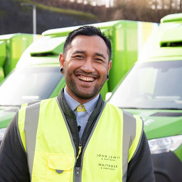 Smiling driver next to fleet of Waitrose vans