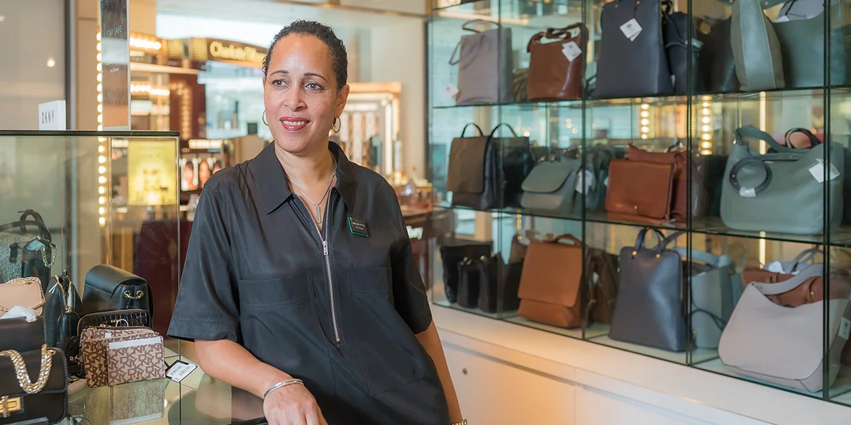 Portrait of a Shop Assistant on the shop floor in front of handbags