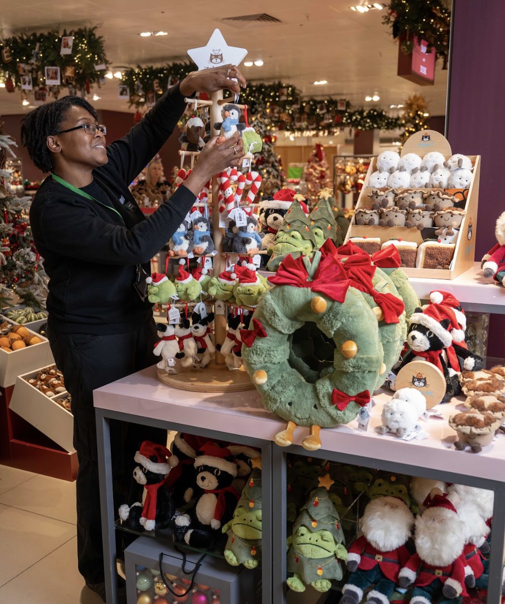 Partner (employee) placing a Christmas decoration on an in store display.